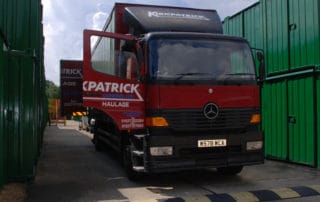 A haulage truck backing up directly to Eversley's storage containers.